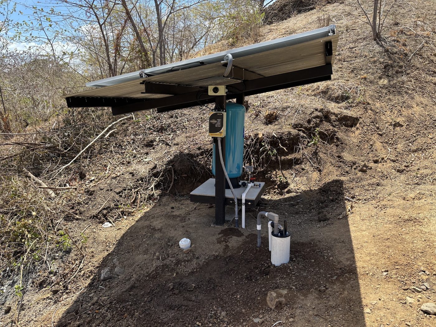 Paneles solares alimentando una bomba de pozo remota con tanque de presión
